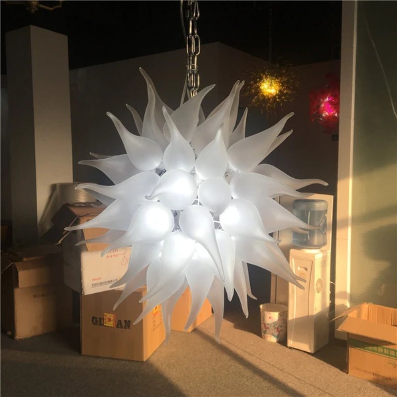 Detailed close-up of a white frosted artisan blown glass chandelier with flame-shaped glass elements in a gallery setting.