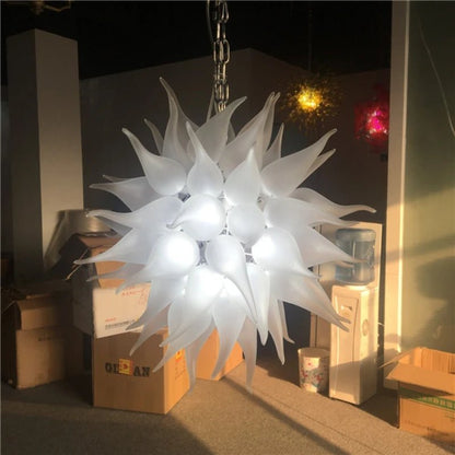 Detailed close-up of a white frosted artisan blown glass chandelier with flame-shaped glass elements in a gallery setting.