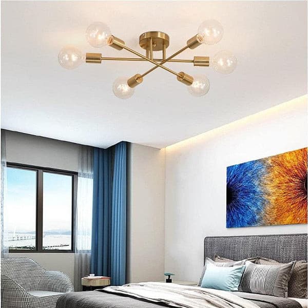 Industrial style linear gold chandelier featuring warm LED Edison bulbs for a cozy bedroom atmosphere.