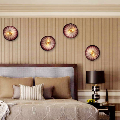 Four glowing glass wall flower lights mounted above a bed headboard, creating a warm and cozy atmosphere.
