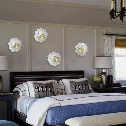 Four glowing white and blue glass wall plates used as decorative ambient lighting above a luxury bed.