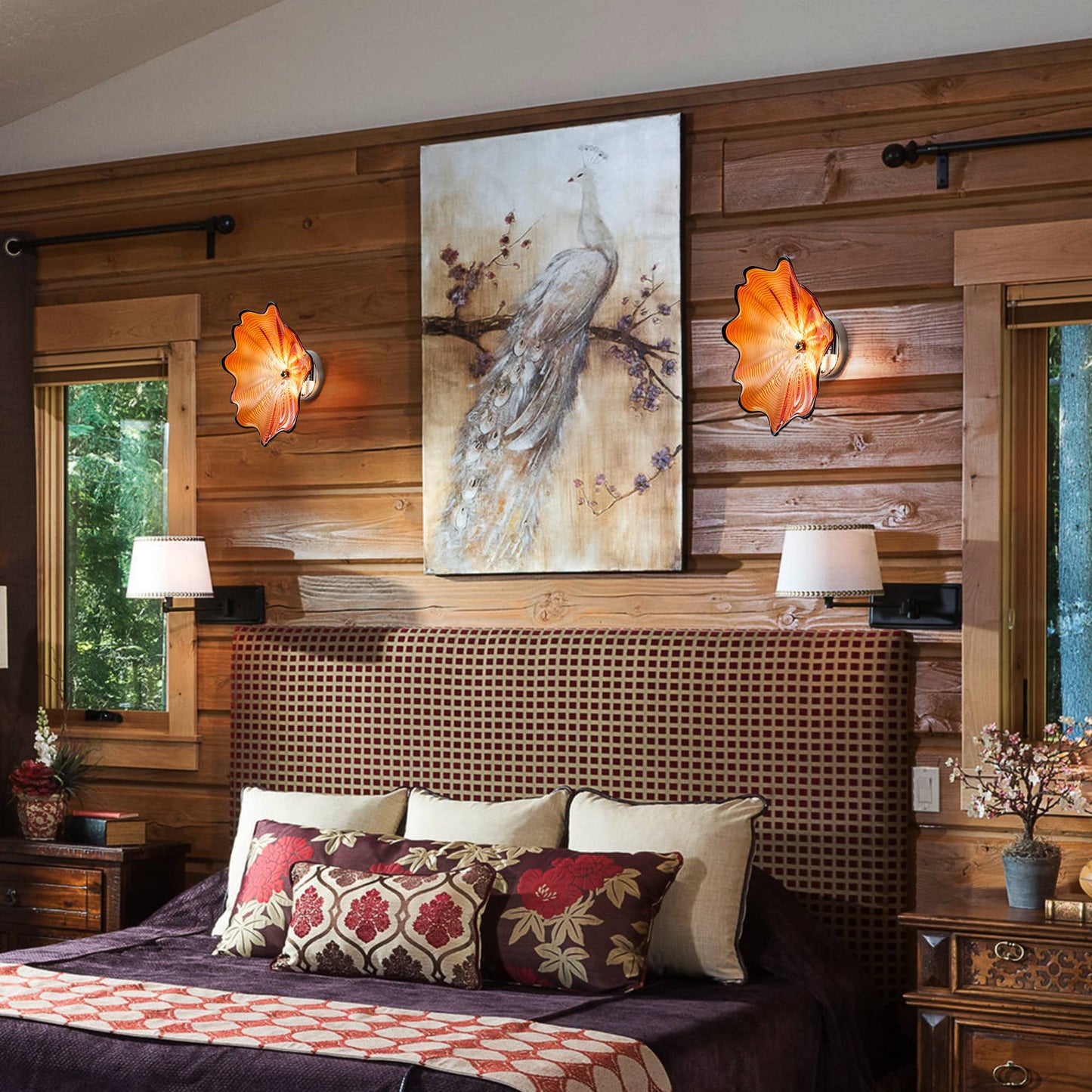 Two orange glass wall lights flanking a piece of art above a headboard in a rustic-modern bedroom.