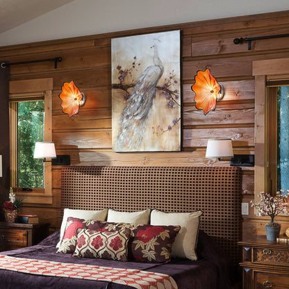 Two orange glass wall lights flanking a piece of art above a headboard in a rustic-modern bedroom.