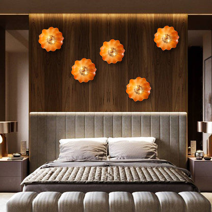 A staggered arrangement of five orange glass flower lights creating a focal point above a master bed.