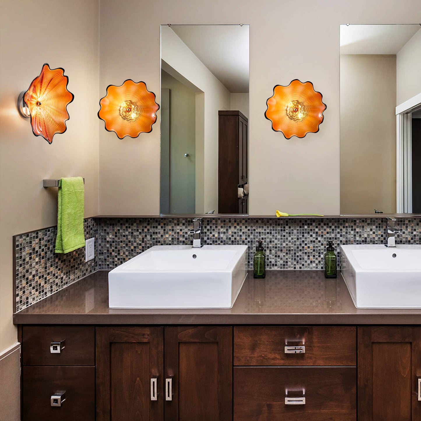 Three orange hand-blown glass wall plates mounted above a double vanity mirror in a luxury bathroom.