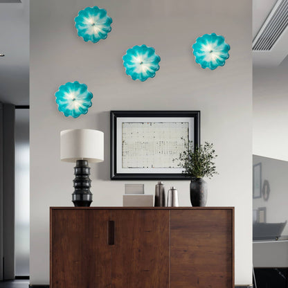 Four hand-blown aqua glass wall art pieces arranged in a group above a dark wood console table.