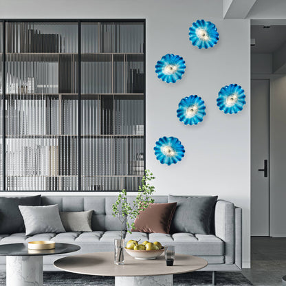 Modern living room decor featuring four blue Murano glass wall flowers arranged on a white wall.