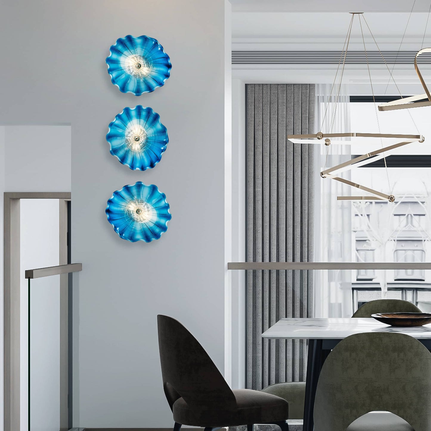Artistic trio of blue glass wall lights installed vertically in a contemporary dining area with high ceilings.