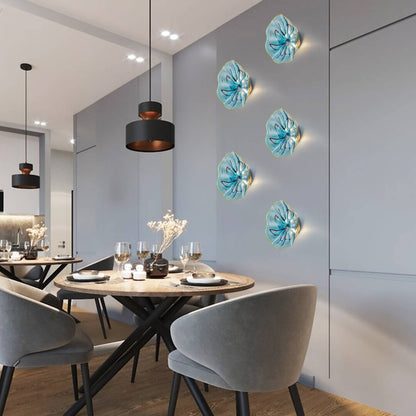 Abstract arrangement of four aqua glass LED wall sconces in a contemporary dining room with dark accents.