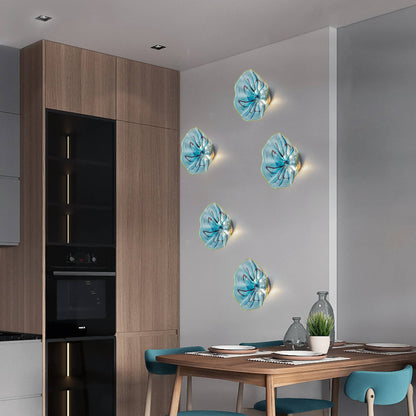 Trio of glowing aqua glass wall flowers installed in a modern kitchen area near dark cabinetry.