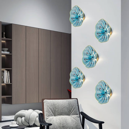 Three vertically arranged aqua glass LED sconces adding a touch of color to a modern gray-walled lounge.